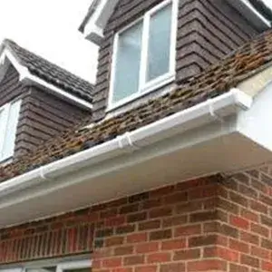 A brick house with a white gutter on the roof.